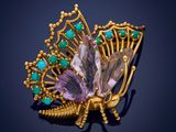 a close up of a butterfly broochle with green and purple stones