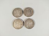 quatre types différents de pièces d'argent sur une surface blanche