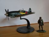 une petite figurine représentant un homme debout à côté d'une maquette d'avion