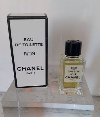 Flacon et coffret de parfum « Eau de Toilette » de Chanel posés sur une table en marbre