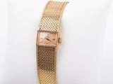 a close up of a gold wrist watch on a white pillow