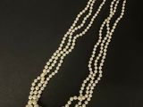 un collier de perles blanches composé de deux rangs de perles sur fond noir