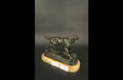 une statue en bronze représentant un chien, posée sur un socle en marbre