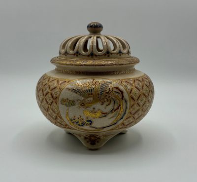 une image représentant un vase décoratif muni d'un couvercle, posé sur une surface blanche
