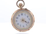 une montre de poche en or avec un cadran blanc sur une surface blanche