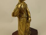 brass figurine of a woman holding a basket on a wooden base
