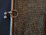 chainmail purse on a blue cloth with a metal clasp