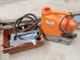 un pulvérisateur orange posé par terre à côté d'une caisse à outils