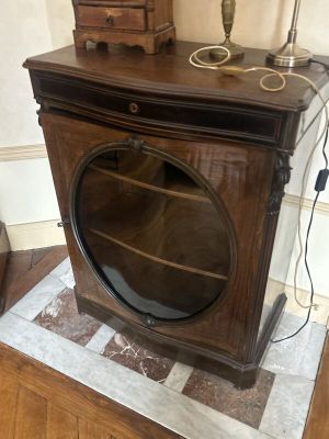 une armoire en bois avec une porte vitrée et une lampe posée dessus