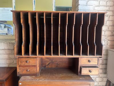 a wooden desk with drawers and a bookcase on top of it