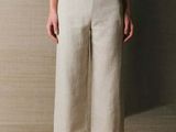 an image of a woman standing in front of a wall wearing a white top and pants