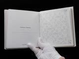 hand in white glove holding a book with a drawing on it