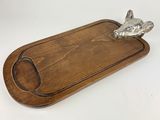 a close up of a wooden cutting board with a metal animal on it