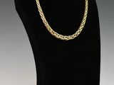 un collier à chaîne en or posé sur un présentoir noir pour mannequin