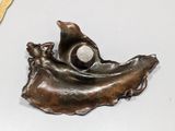 a bronze sculpture of a bird on a leaf