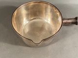 a small metal bowl with a handle on a table