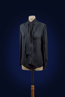 black shirt on a mannequin stand against a dark blue background