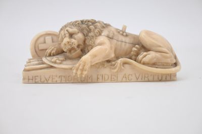 sculpture of a lion laying on top of a wooden plaque