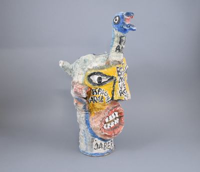 a ceramic sculpture of a bird with a face on it ' s head