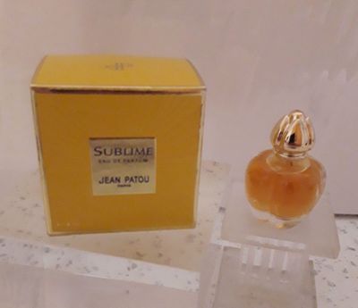 un flacon de parfum dans une boîte, posé sur une table à côté d'une boîte de parfum