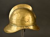 a gold helmet on a metal stand against a black background