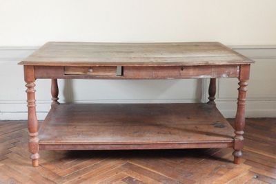 une table en bois avec un tiroir en dessous, posée sur un parquet en bois massif
