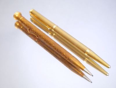 two pens sitting next to each other on top of a white surface