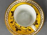 yellow and white coffee cup and saucer with gold decoration