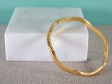a gold bracelet sitting on top of a marble block