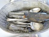 beaucoup de cuillères en argent dans un panier avec un couteau