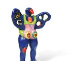 brightly colored figurine of a man holding a pair of scissors in his right hand