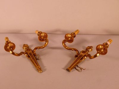 pair of gold plated wall sconces on a white surface