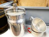a silver tea pot sitting on a table next to a silver cup