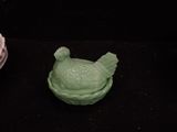 a green bird figurine sitting next to a purple bowl