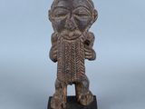 une vieille statue en bois représentant un homme barbu coiffé d'un chapeau