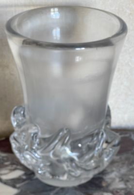 un verre posé sur une table, à côté d'un vase