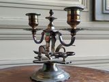un candélabre en argent posé sur une table en bois devant une fenêtre