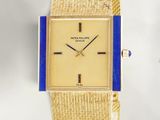 an image of a gold watch with a blue band on a white background