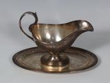 a silver gravy on a silver plate on a table