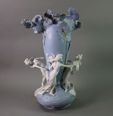 a blue vase with a statue and flowers in it