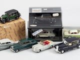 Plusieurs petites voitures sont rangées dans une boîte, à côté d'une pile de boîtes.