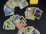 beaucoup de cartes Pokémon et une boîte jaune sur la table