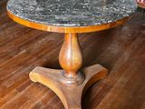 une table avec un plateau en marbre posée sur un parquet
