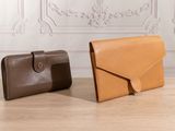 two leather wallets sitting on top of a table next to each other