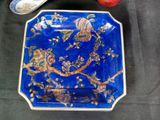 a blue plate with a bird on it next to a spoon
