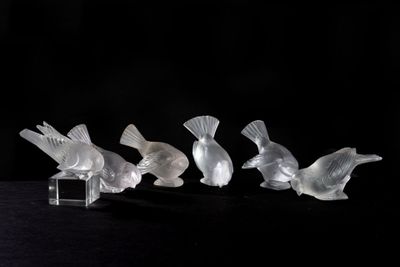 four glass birds sitting on a black surface with a black background