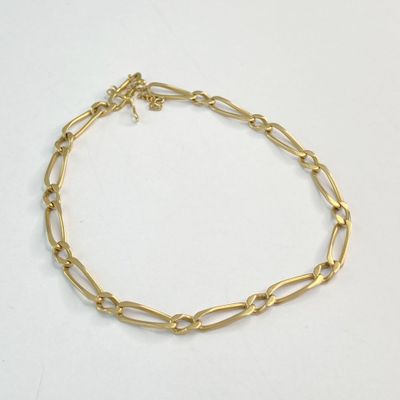 gros plan d'un bracelet en chaîne en or sur une surface blanche