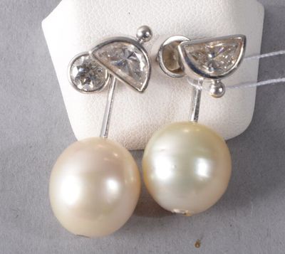 pair of pearl and diamond earrings on display on white cloth