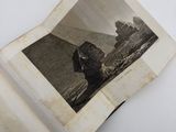 an old photo of a man sitting on a rock