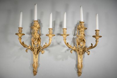 pair of gilded wall sconces with candles on each of them